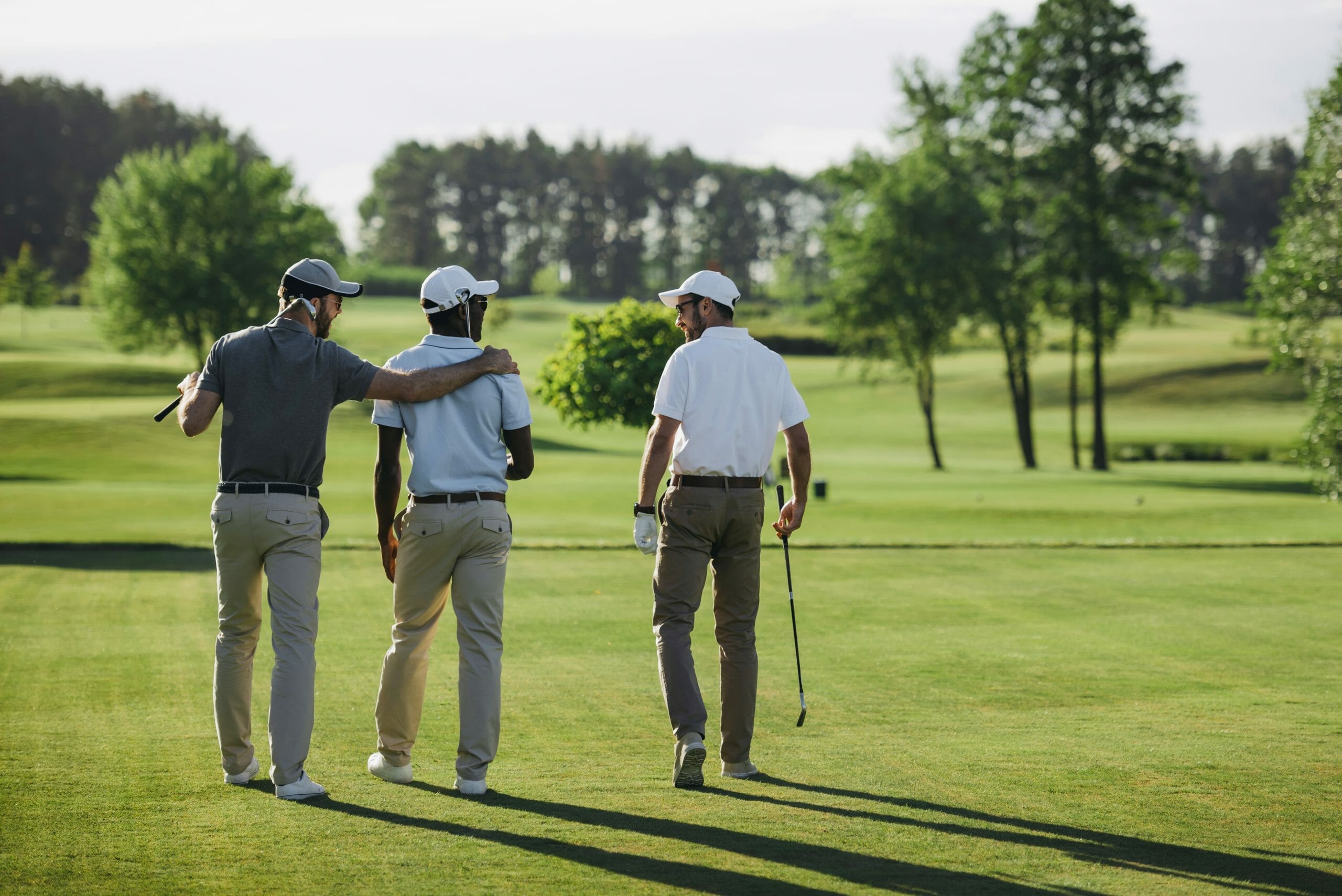 rear view of golfers walking arm over shoulder